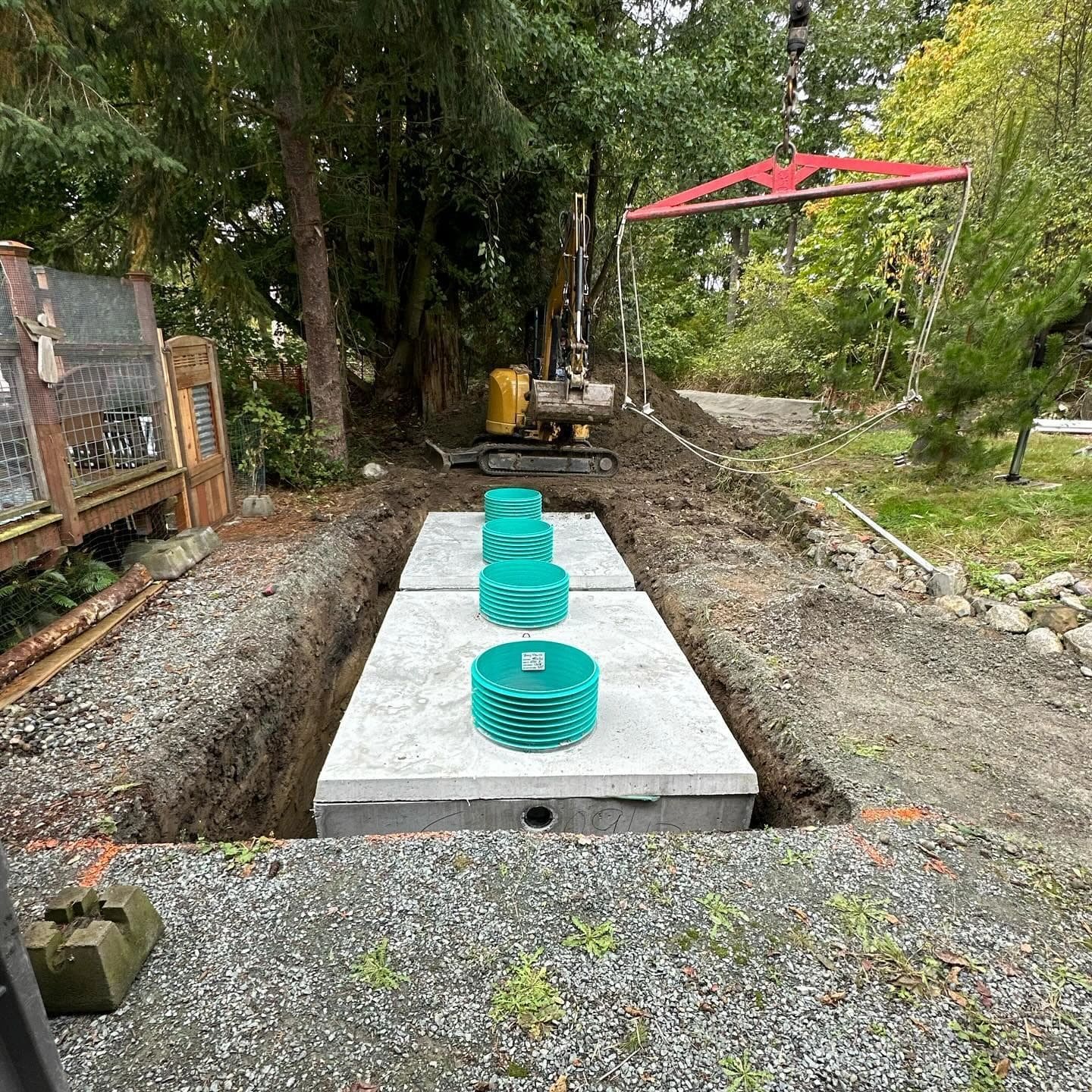 New septic tanks with risers being craned into an excavation.