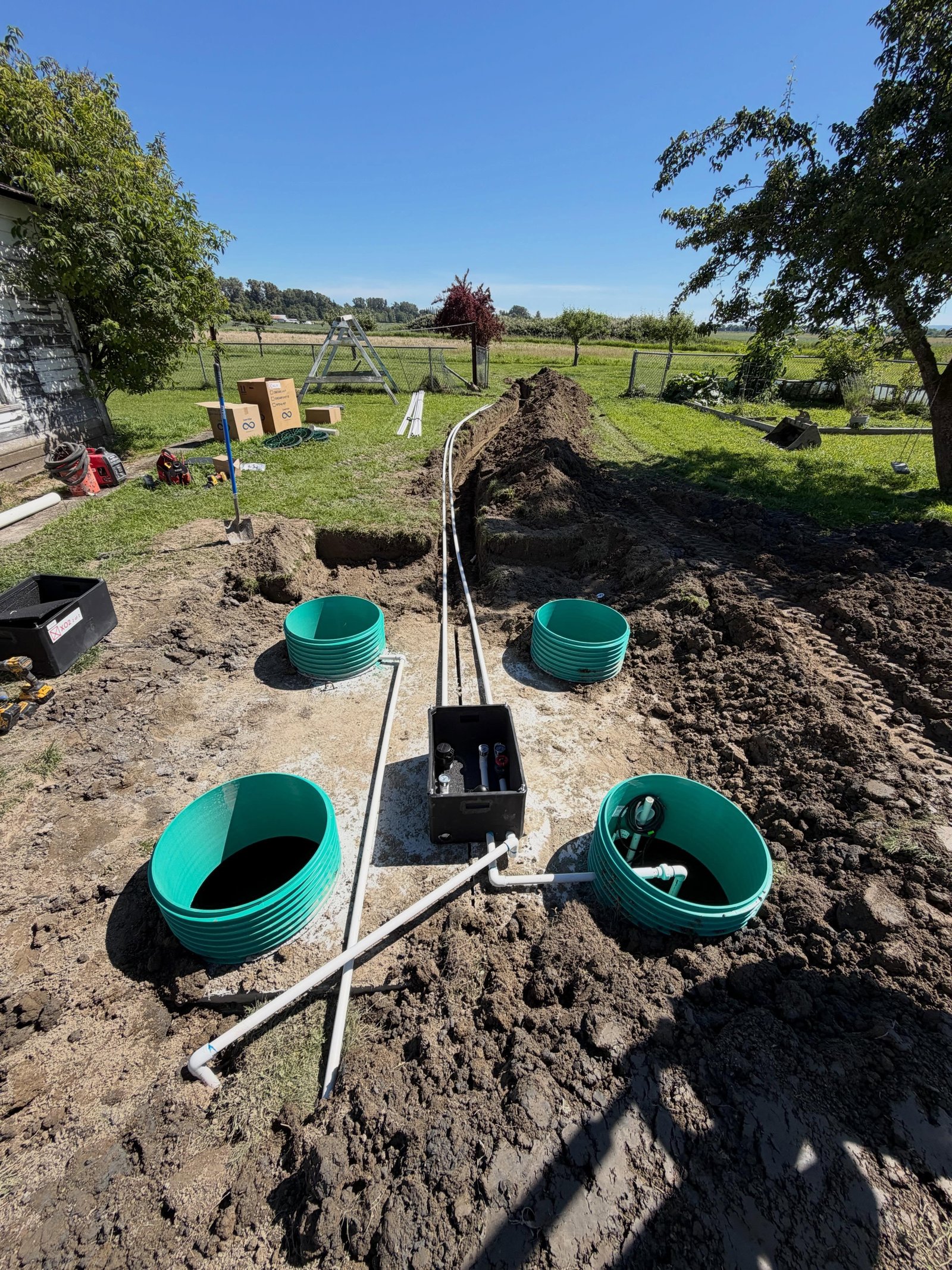 A concrete septic tank with green risers and new transport line plumbing during installation.
