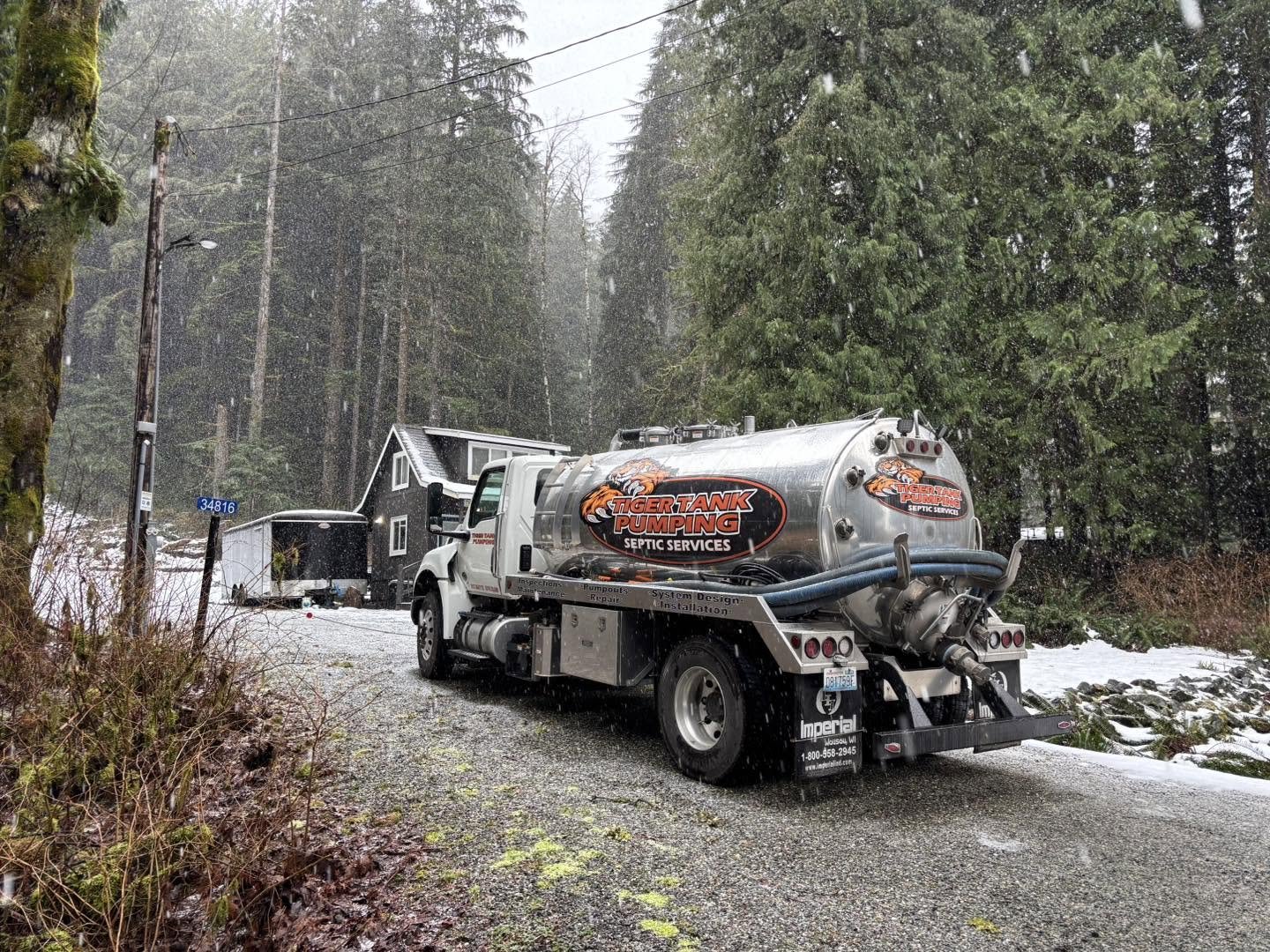 A Tiger Tank Pumping truck pumping a septic tank in falling snow.